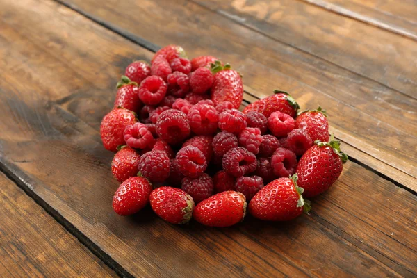 Herzförmige Erdbeeren und Himbeeren auf Holzgrund — Stockfoto
