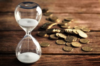 Kum saati ve sikkeler üzerinde ahşap masa yakın çekim