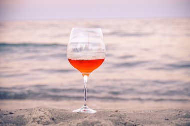 Romantik bir bardak şarap renkli gün batımında sahilde oturmuş