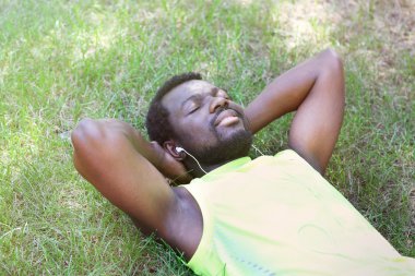 Park yeşil çim üzerinde kulaklık ile Afrika kökenli Amerikalı adam