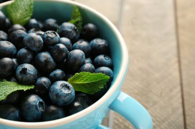 Ahşap masa üzerinde Kupası'nda taze yaban mersini yakın çekim