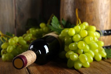 Şarap şişesi ahşap arka plan üzerinde beyaz üzüm