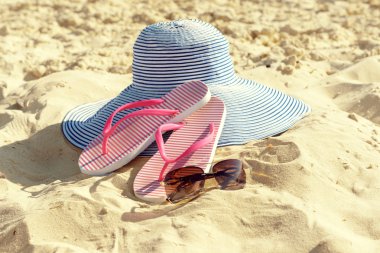 Kum plaj portre üzerinde flip floplar, güneş gözlüğü ve şapka