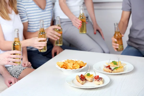 Vrienden handen met flessen bier en snacks, close-up — Stockfoto