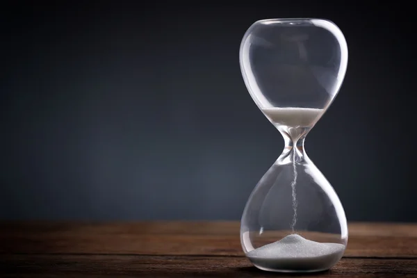 Reloj de arena sobre mesa de madera sobre fondo gris —  Fotos de Stock