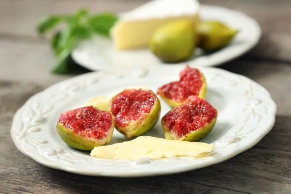Ripe figs and cheese on plate, on wooden background — Stock Photo, Image