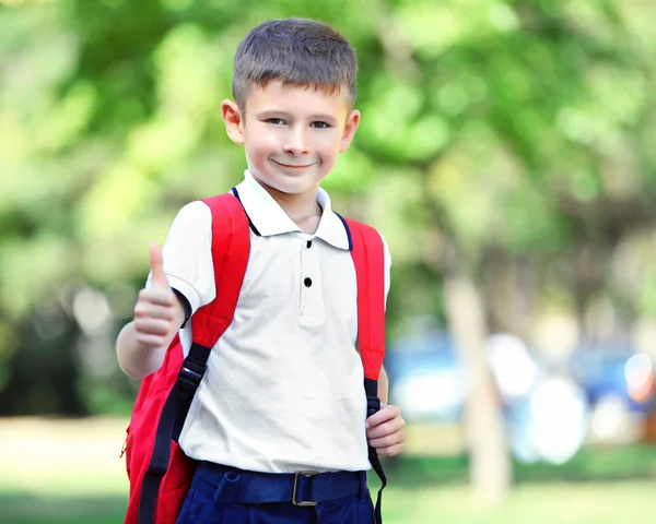 Маленький хлопчик з великою шкільною сумкою, надворі — стокове фото