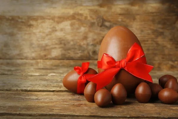 Un gros et petit oeuf de Pâques en chocolat sur fond en bois — Photo