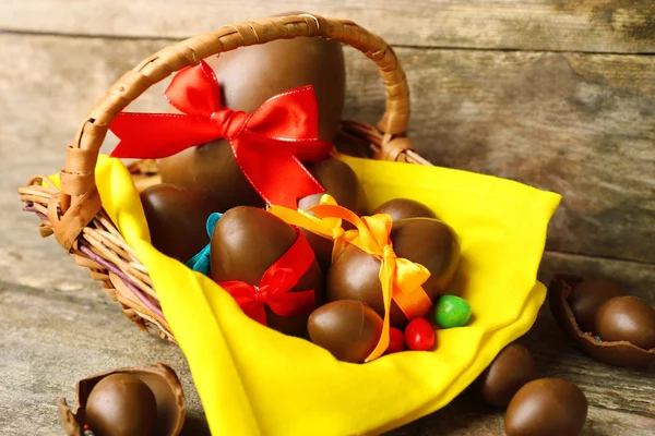 Huevos de Pascua de chocolate en cesta sobre fondo de madera — Foto de Stock