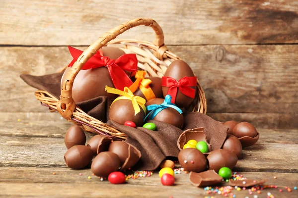 Chocolate Easter eggs in basket on wooden background — Stock Photo, Image