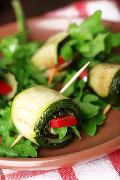 Rotoli di zucchine con formaggio, peperoni e rucola sul piatto, primo piano, sullo sfondo della tavola — Foto Stock