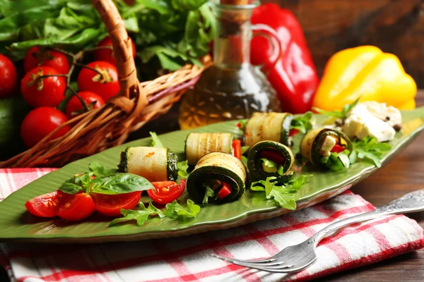 Rollos de calabacín con queso, pimientos y rúcula en el plato, primer plano, sobre fondo de mesa — Foto de Stock