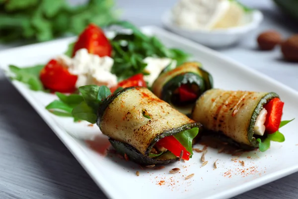 Rollos de calabacín con queso, pimientos y rúcula en el plato, primer plano — Foto de Stock