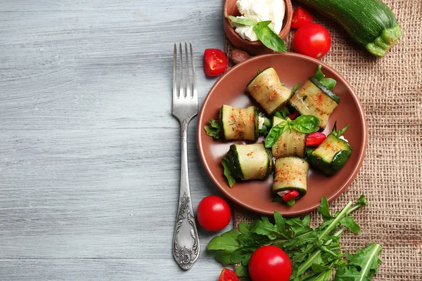 Salada com rolos de abobrinha e arugula na placa, no fundo da mesa — Fotografia de Stock