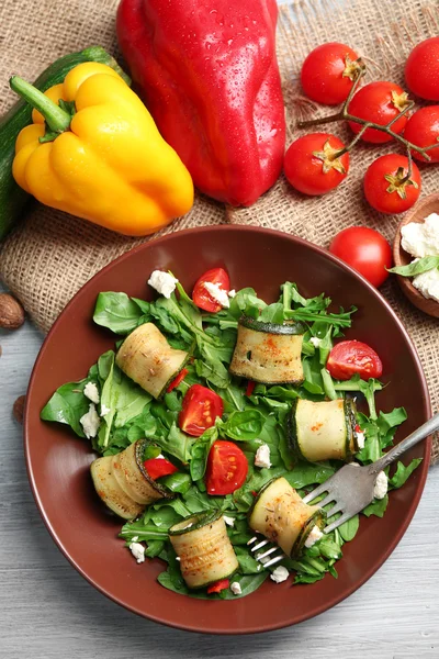 Salade avec roquette et courgettes roulées sur assiette, sur fond de table — Photo