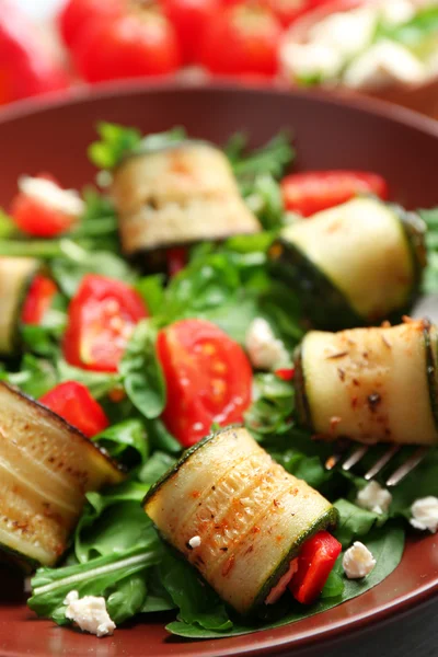 Salada com rolos de abobrinha e arugula na placa, no fundo da mesa — Fotografia de Stock