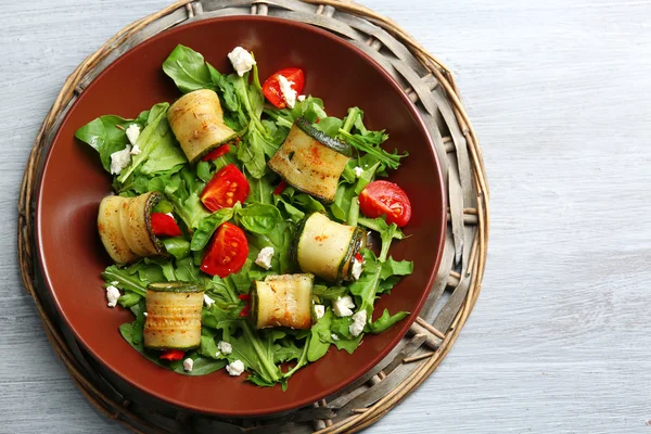 Salat mit Rucola und Zucchini-Rollen auf Teller, auf Tischhintergrund — Stockfoto