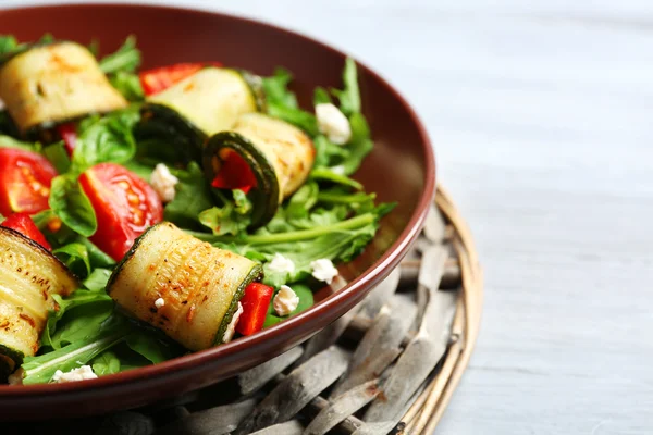 Salad with arugula and zucchini rolls on plate, on table background — Stock Photo, Image