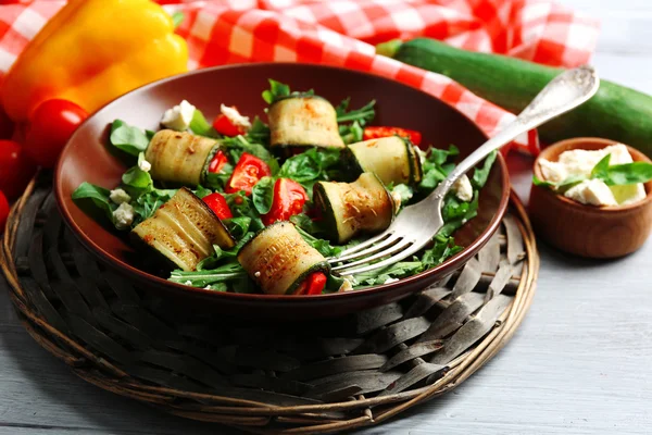 Salada com rolos de abobrinha e arugula na placa, no fundo da mesa — Fotografia de Stock