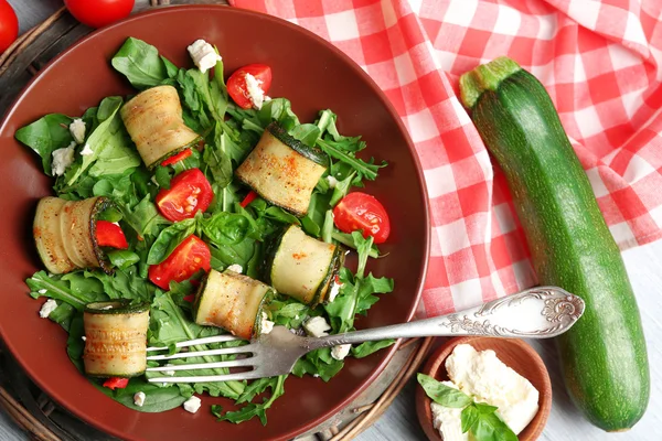 Salad with arugula and zucchini rolls on plate, on table background — Stock Photo, Image
