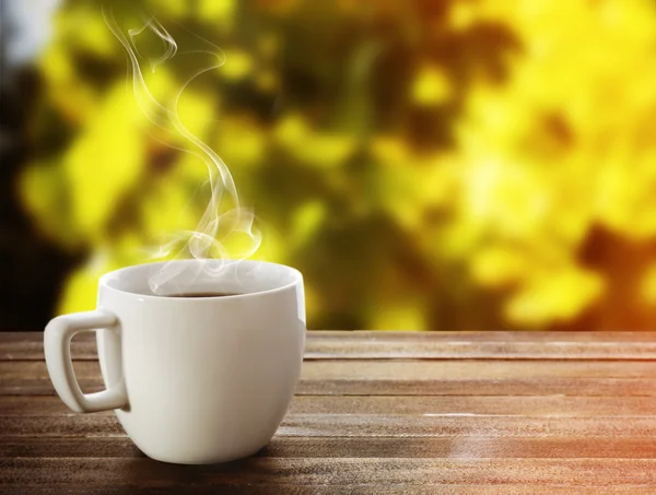 Taza de café en la mesa sobre fondo brillante — Foto de Stock