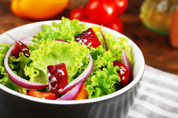 Bowl of fresh green salad on table with napkin, closeup — Stock Photo, Image