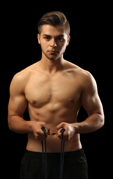 Muscle young man exercising with resistance band on dark background — Stock Photo, Image
