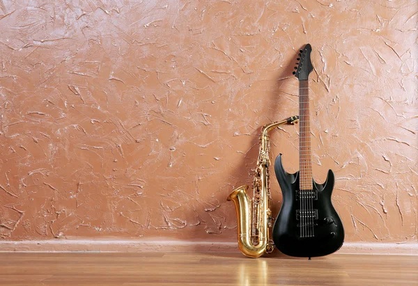 Guitarra elétrica e saxofone no fundo da parede marrom — Fotografia de Stock