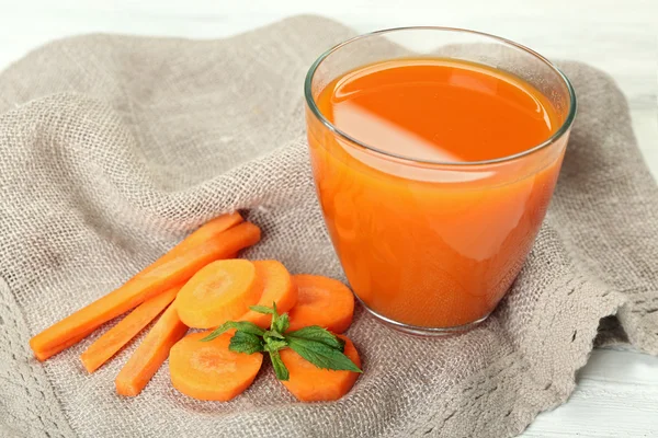 Glass of carrot juice with vegetable slices on table close up — Stock Photo, Image