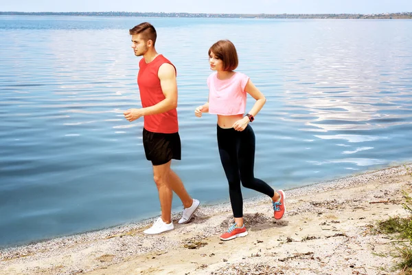 Unga människor jogging på stranden — Stockfoto