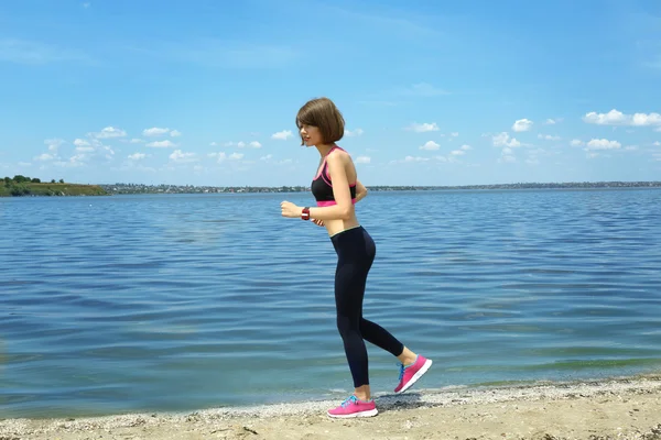 Jonge vrouw joggen op strand — Stockfoto
