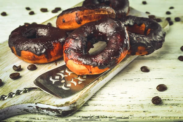 Delicious doughnuts with chocolate icing and coffee beans on table close up — Stock Photo, Image