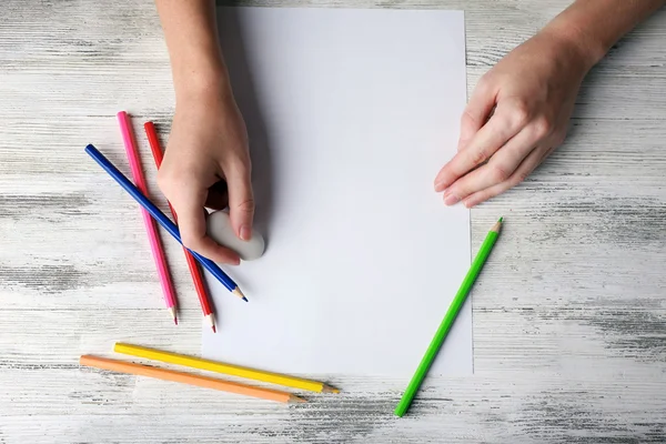 Main avec crayons de couleur et feuille de papier vierge sur table en bois — Photo