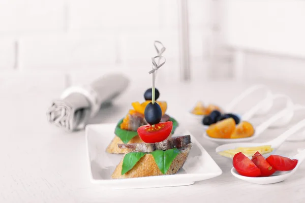 Smakelijke canapeetjes op houten tafel, close-up — Stockfoto