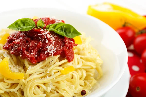 Спагетті з томатним соусом і сиром на білій тарілці, на кольоровому дерев'яному фоні — стокове фото