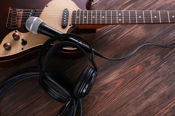 Elektrická kytara s mikrofonem a sluchátky na dřevěný stůl zblízka — Stock fotografie