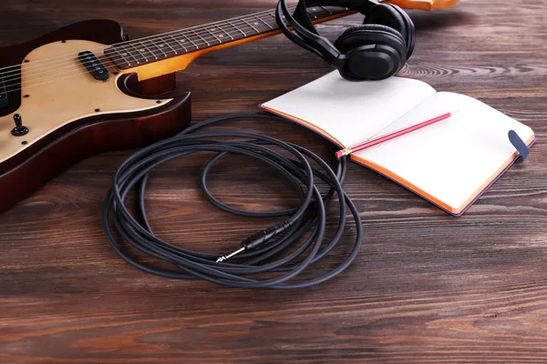 Guitarra eléctrica con auriculares y portátil en mesa de madera de cerca — Foto de Stock