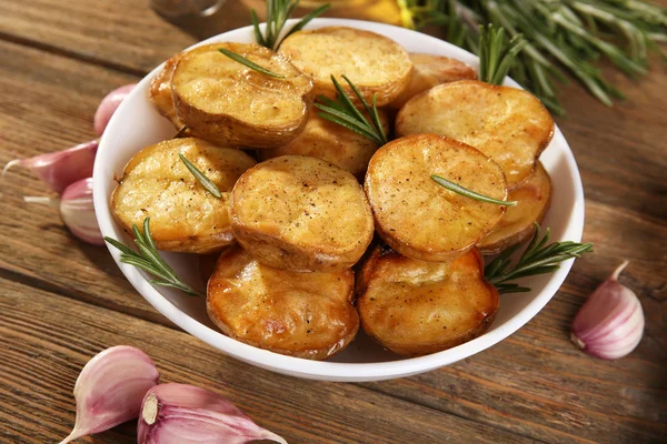 Cartofi prăjiți delicioși cu rozmarin în castron pe masă aproape — Fotografie, imagine de stoc