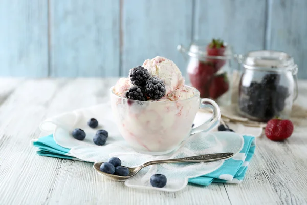 Вкусное мороженое со свежими замороженными ягодами, на фоне цвета дерева — стоковое фото