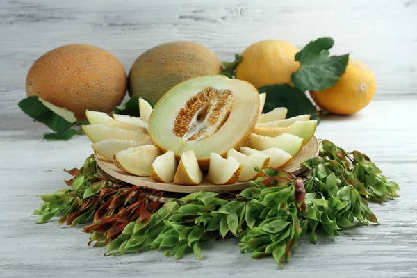 Rijpe meloenen met groene bladeren op houten tafel close-up — Stockfoto