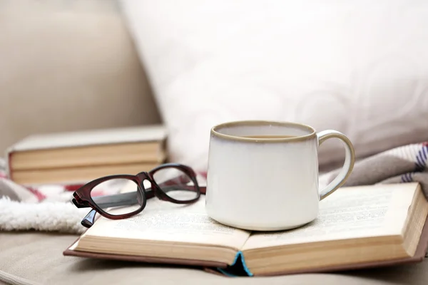 Cup of coffee with book on sofa in living room — Stock Photo, Image