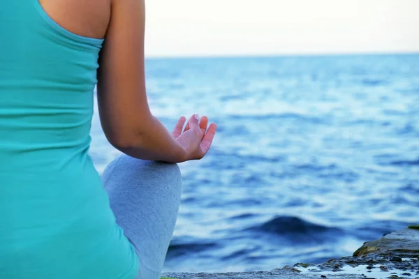 Mujer joven practicando yoga en la orilla del mar — Foto de Stock