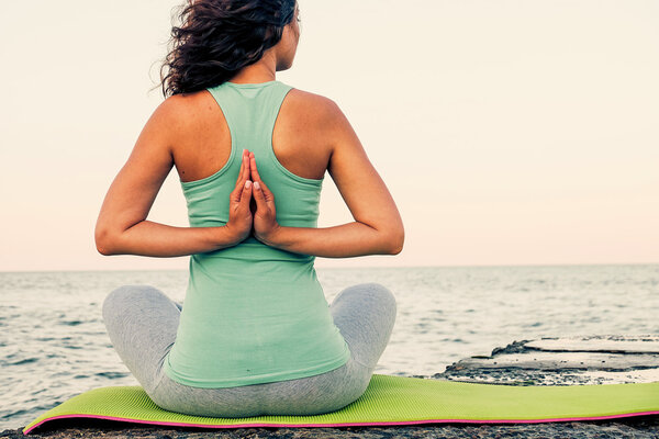 Young woman practicing yoga at seashore