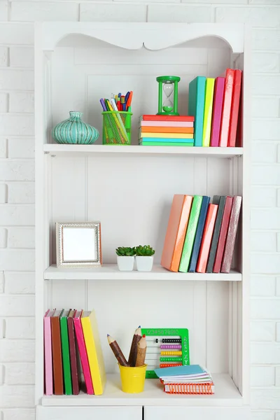 Livros e decoração em prateleiras no armário — Fotografia de Stock