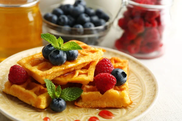 Süße hausgemachte Waffeln mit Waldbeeren und Soße auf Tischhintergrund — Stockfoto