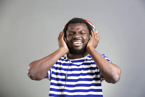 African American man with headphones on grey background — Stock Photo, Image