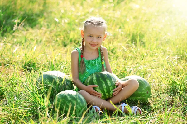 Small girl with watermelons on lawn — Stock Photo, Image