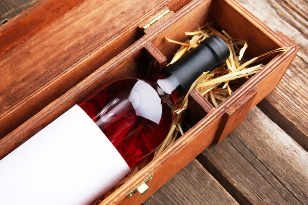 Expensive wine in elegant case with straw on wooden background — Stock Photo, Image