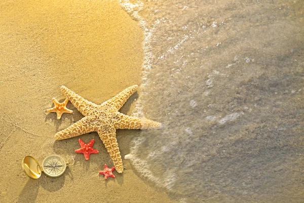 Bússola com estrelas do mar na areia — Fotografia de Stock