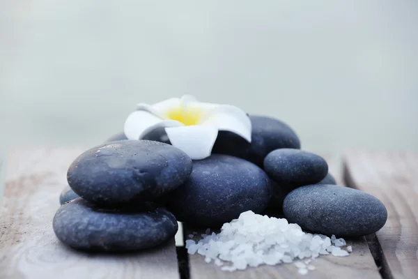 Composition of pebbles and fragipani flower on wooden background — Stock Photo, Image